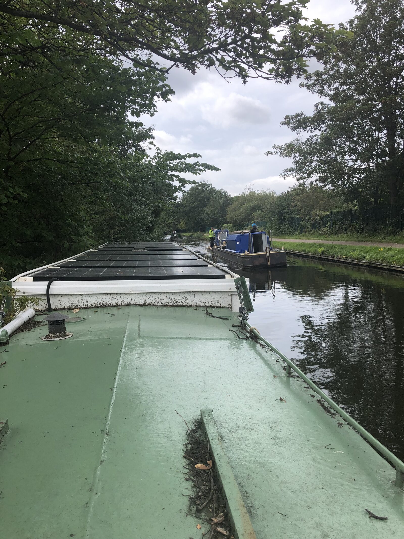 A narrowboat on a canal with solar panels along its roof, part of the University of Birmingham hydrogen fuel-cell boat project